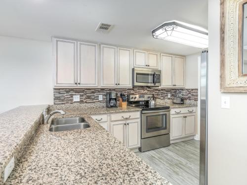 a kitchen with white cabinets and granite counter tops at Bay View Villas 107 in Tybee Island