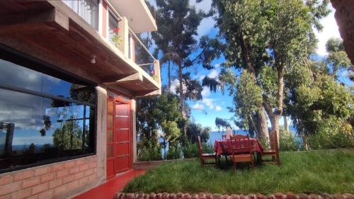 un tavolo rosso sull'erba accanto a un edificio di Illariywasi Homestay Comunidad Pueblo Isla Amantani a Ocosuyo