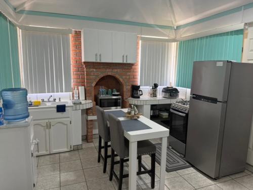 a kitchen with a refrigerator and a table with chairs at Seaside Adventure Lodging in Ensenada