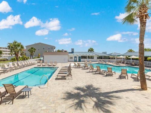a pool with lounge chairs and a palm tree at Atlantic Ocean 2 in Tybee Island