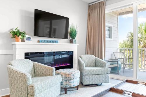 a living room with two chairs and a fireplace with a tv at Atlantic Ocean 2 in Tybee Island