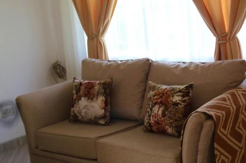 a couch with three pillows sitting in a living room at 2 bedroomed house with a lovely garden - 2177 in Umtali