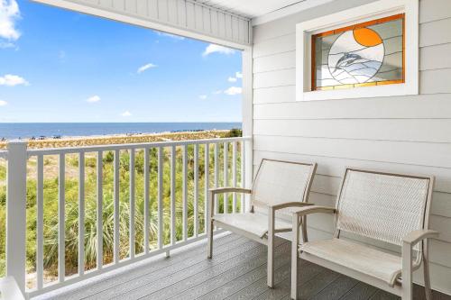 two chairs on a porch with a view of the beach at Atlantic Ocean 2 in Tybee Island