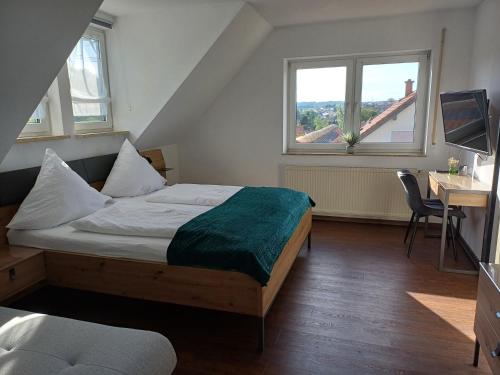 a bedroom with a bed and a desk and two windows at Gästehaus am Radweg in Herbstein
