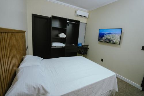a bedroom with a white bed and a black shelf at Residência TCA in Brasilia