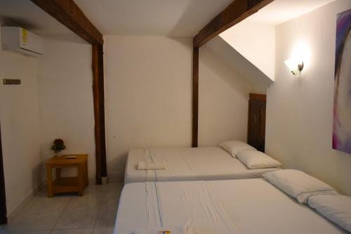 two beds in a small room with a window at Hotel Agroturistico Palma Vino in Arboletes