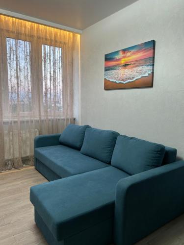 a living room with a blue couch and two windows at ML Apartments in Odesa