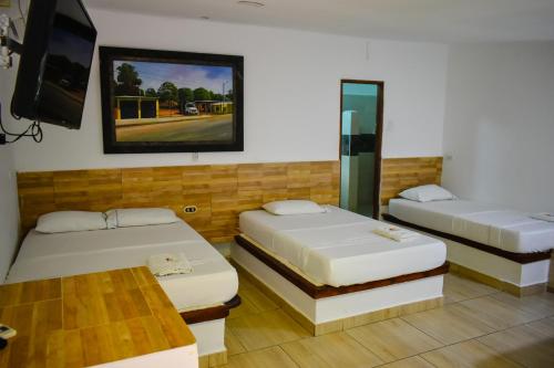 a room with two beds and a tv and a table at Hotel Agroturistico Palma Vino in Arboletes