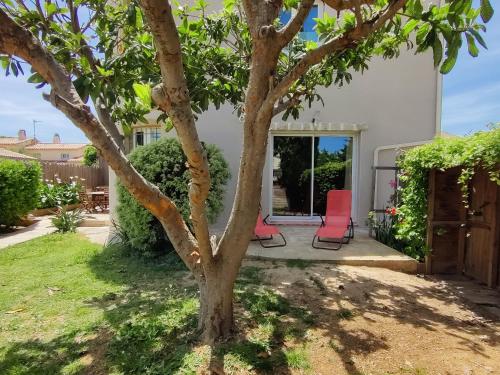 un patio avec deux chaises rouges à côté d'un arbre dans l'établissement Villa Douceur de Vivre à 15 min de la plage, à Villeneuve-lès-Maguelone