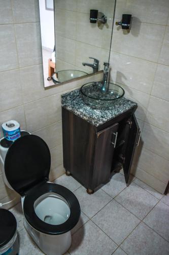 a bathroom with a black toilet and a sink at Hotel Agroturistico Palma Vino in Arboletes