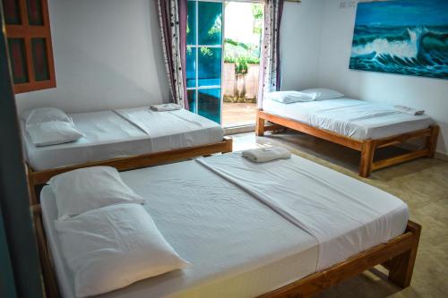 three beds in a room with a window at Hotel Agroturistico Palma Vino in Arboletes