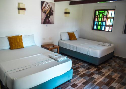 a bedroom with two beds and a window at Hotel Agroturistico Palma Vino in Arboletes