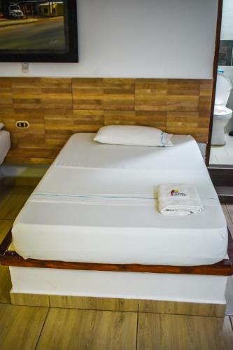 a large white bed with a wooden headboard at Hotel Agroturistico Palma Vino in Arboletes