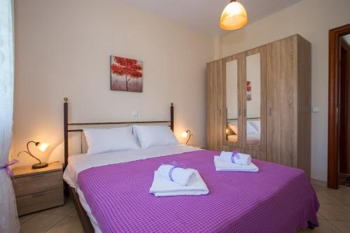 リメナリアにあるMantos Apartmentのベッドルーム1室(紫色のベッド1台、タオル付)