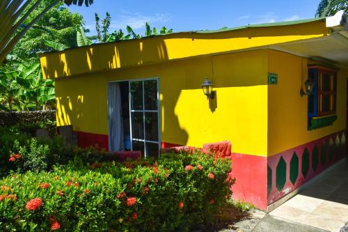 a colorful house with a garden in front of it at Hotel Agroturistico Palma Vino in Arboletes