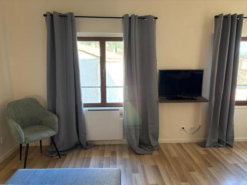 a room with a window with a chair and a television at Coeur de Moustiers pour 2 personnes in Moustiers-Sainte-Marie