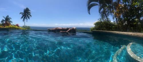 a couple of people in a swimming pool at Beachfront Villa - House of Bamboo, Infinity Pool in Savusavu