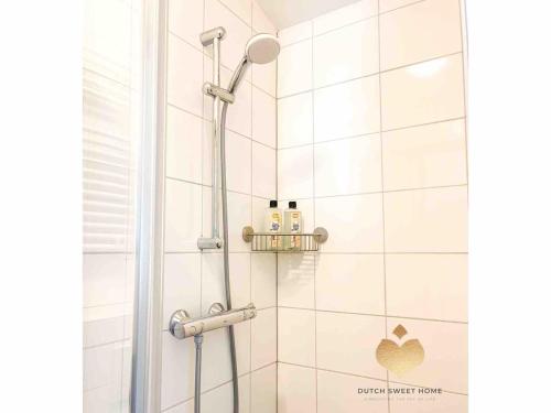 a bathroom with a shower with white tiles at The Soultree - Stylish nature cottage near Schoorl dunes & Bergen beach in Warmenhuizen
