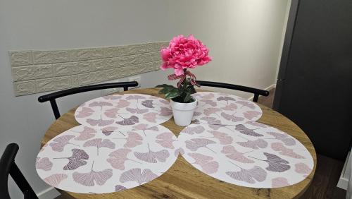 a table with a pink flower in a vase on it at Garden Lemon Tree Villa in Tirana