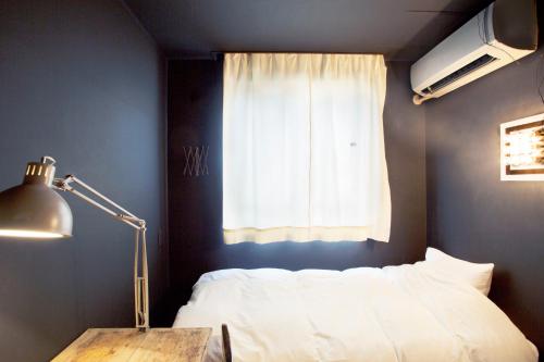 a bedroom with a bed and a desk and a window at Apartment Hotel Shinjuku in Tokyo