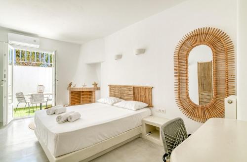 Un dormitorio blanco con una cama y un espejo. en Olive & Stone Residence, en Aliki