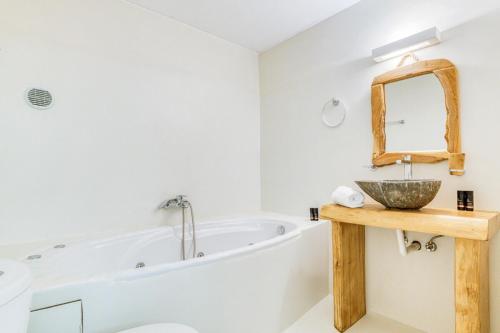 Un baño con bañera, lavabo y espejo. en Olive & Stone Residence, en Aliki