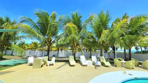 a row of chairs and a swimming pool with palm trees at Apartamento familiar frente al mar in Palo Grande
