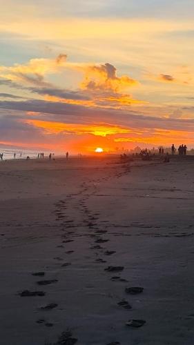 a sunset on a beach with footprints in the sand at Apartamento familiar frente al mar in Palo Grande