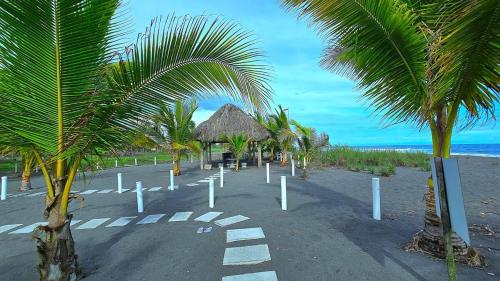 a sandy beach with palm trees and a strawilion at Apartamento familiar frente al mar in Palo Grande