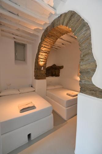 two beds in a room with an archway at Kariki Green Triantaros Tinos in Triandáros