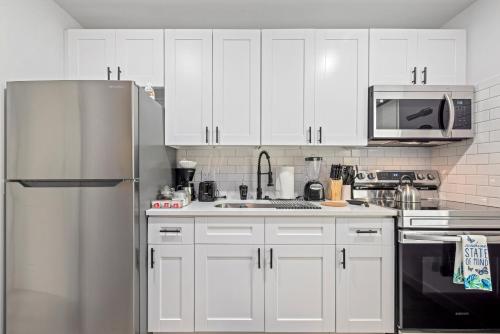 een keuken met witte kasten en een roestvrijstalen koelkast bij Downtown Heights Flat Games TVs WiFi Pets in Houston