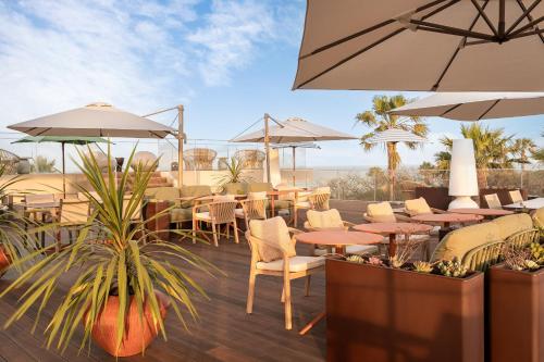 a restaurant with tables and chairs and umbrellas at Kimpton Atlantico Algarve by IHG in Albufeira