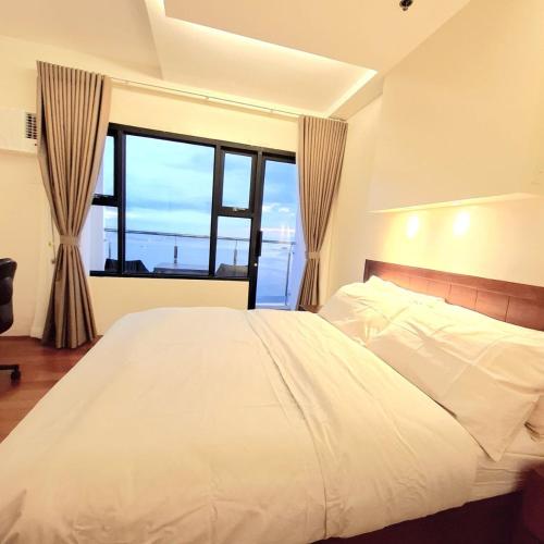 a bedroom with a white bed and a large window at BREATHTAKING BAYVIEWS - 1-5 BR Luxury and Superior Condos with Panoramic Bay Views, Balcony, Gym, Pool & Netflix - Housekeeping Available - in Manila