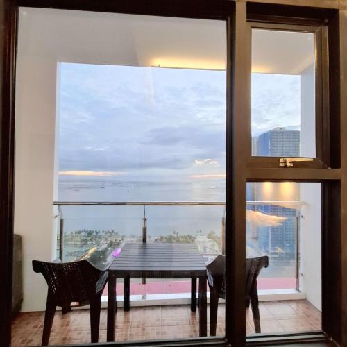 a dining room table with a view of a balcony at BREATHTAKING BAYVIEWS - 1-5 BR Luxury and Superior Condos with Panoramic Bay Views, Balcony, Gym, Pool & Netflix - Housekeeping Available - in Manila