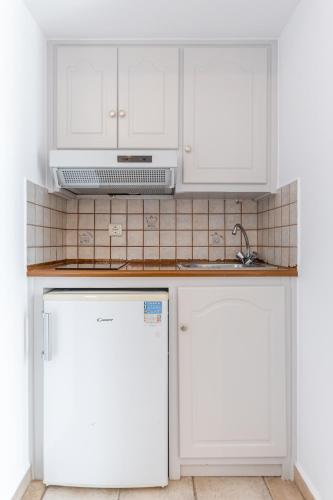 a kitchen with white cabinets and a white refrigerator at Golden Bay in Agios Prokopios