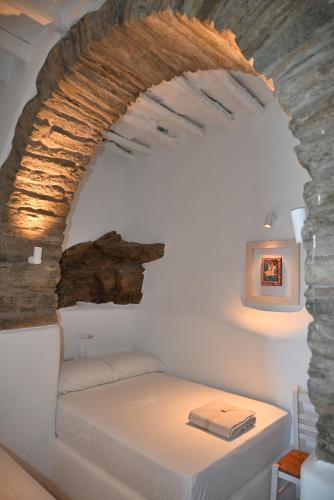 a bed in a room with a stone wall at Kariki Green Triantaros Tinos in Triandáros