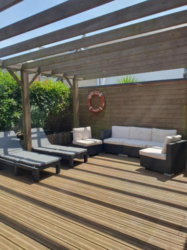 une terrasse en bois avec des canapés et une pergola dans l'établissement Maison Les Aygals 300 m de la plage, 3 suites parentales, à Saint-Pierre-Quiberon
