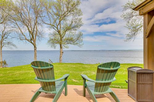 two green chairs sitting on a patio overlooking the water at Lake Champlain Family Retreat with Deck and Yard in North Hero