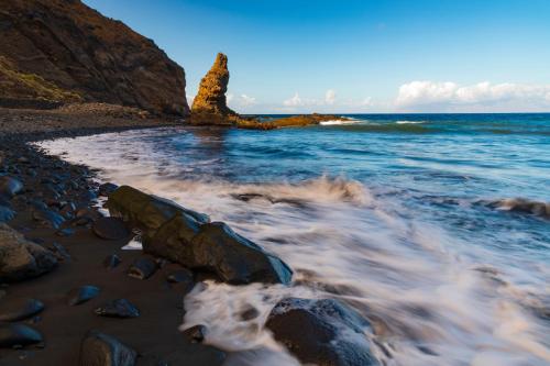 a rocky beach with a rock formation in the water at Banana Garden Suites in Hermigua