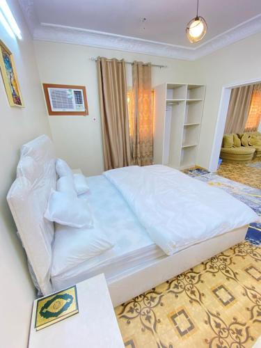 a large white bed in a bedroom with a table at نزل القمريه in Taif