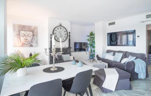 a living room with a table and a clock on the wall at Alma's Dream Estepona in Estepona