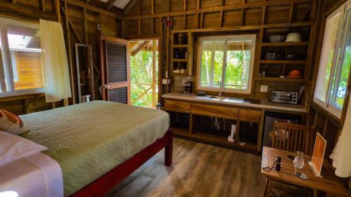 a bedroom with a bed and a sink and windows at Toucan Hill Lodge in Bocas del Toro