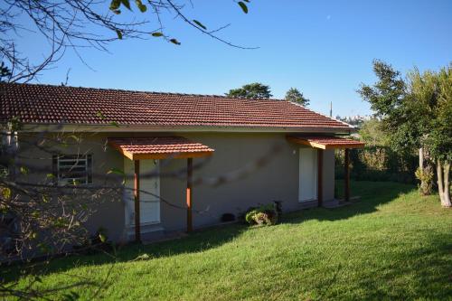 a small white house with a grass yard at Suítes Celeste, Charme no Vale dos Vinhedos com Banheira e Café da Manhã Colonial Incluso in Bento Gonçalves