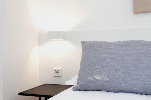 a bed with a blue pillow and a table at Sunset Split Rooms in Podstrana