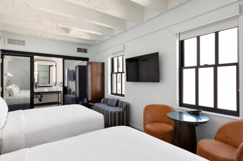 a hotel room with two beds and a tv at The Guild Hotel San Diego Downtown, a Marriott Tribute Portfolio Hotel in San Diego