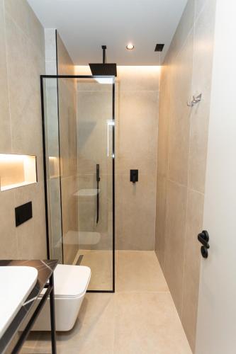 a bathroom with a shower with a toilet and a sink at South Inn Hotel in Vlorë
