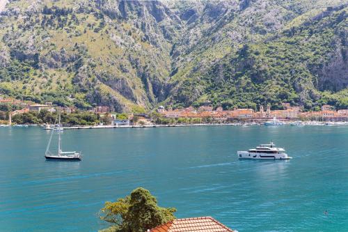 two boats in a large body of water with mountains at Apartments Dončić in Kotor