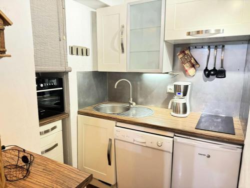 une cuisine avec des armoires blanches et un évier dans l'établissement Résidence Clairiere - La Clairière 20 - Très joli studio, calme et rénové avec goût MAE-0773, à Valmorel