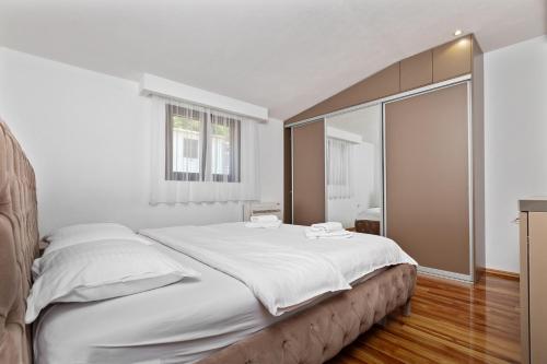 a bedroom with a large bed with white sheets at Apartments Dončić in Kotor