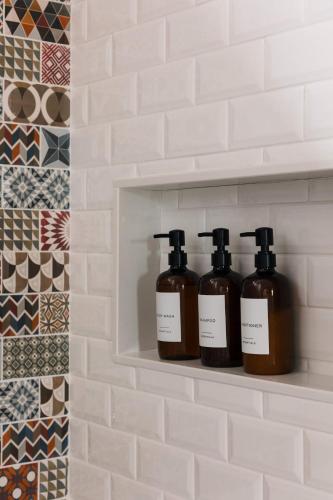 three bottles of soap sitting on a shelf in a bathroom at SquirrelHaus PEC in Hillier